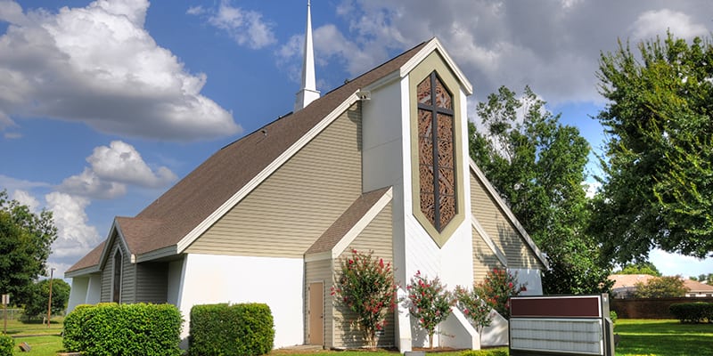 Beautiful christian church with white steeple cross and blue sky